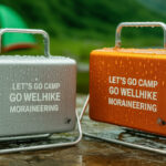 A flat lay image showcasing various camping gear and survival tools arranged on a rustic wooden surface, with the title "30 Genius Camping Hacks That Will Change Your Experience" overlaid in bold white text.